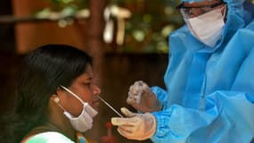 Un personnel médical portant un équipement protectif teste un femme au Covid-19 le 26 août 2020 à Siliguri en Inde