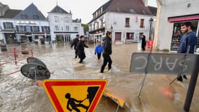 Une résidente locale porte une pompe à eau alors qu'elle marche dans une rue inondée du centre de
Cloyes-les-Trois-Rivières, centre de la France, le 11 octobre 2024.