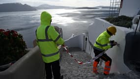 Des employés municipaux coupent l'accès à une ruelle du village d'Oia, à Santorin, le 5 février 2025, après une série de secousses enregistrées sur l'île grecque. 