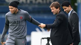 L'attaquant Kylian Mbappé salue le directeur sportif brésilien Leonardo, sous les yeux du président qatari du Paris Saint-Germain, Nasser Al-Khelaifi, le 27 septembre 2021, à la veille du match de groupes de Ligue des Champions contre Manchester City au Parc des Princes