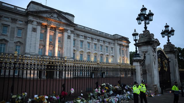 Des fleurs et des officiers de police devant le palais de Buckingham, à Londres, le 9 septembre 2022 au lendemain de la mort de la reine Elizabeth II