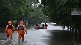 Des sauveteurs aident à évacuer un habitant d'une zone inondée dans la ville de Kherson, le 11 juin 2023. 