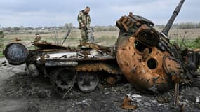 Des militaires ukrainiens examinent un char russe détruit en bordure de route à Rusaniv, dans la région de Kiev, le 16 avril 2022
