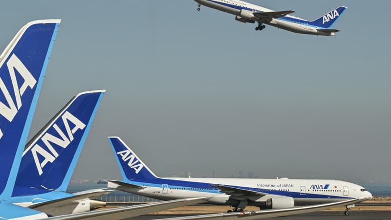 Cette photo prise le 30 janvier 2024 montre un avion de passagers de la compagnie aérienne japonaise All Nippon Airways (ANA) (en haut) décollant alors qu'un autre (à droite) passe devant d'autres avions garés aux portes de l'aéroport international de Tokyo à Haneda, à Tokyo.