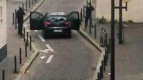 Les deux tireurs encagoulés, menacent une voiture de police après avoir attaqué Charlie Hebdo, ce mercredi matin.
