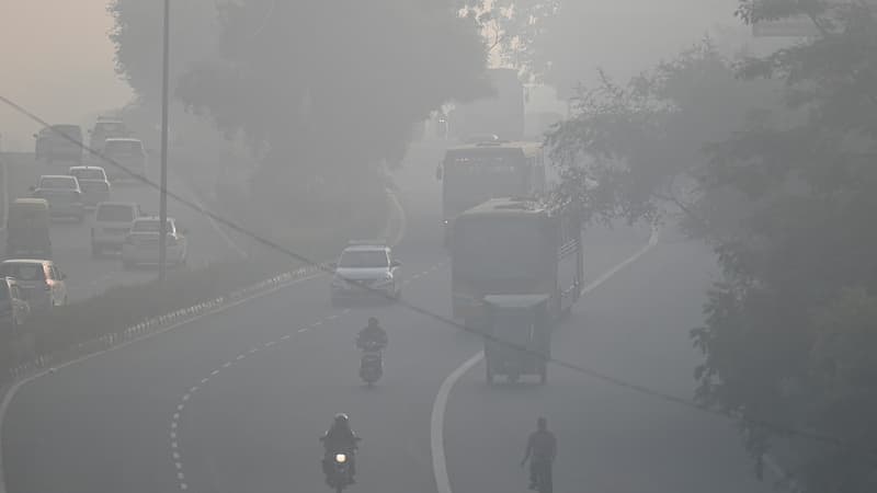 Des habitants de banlieues roulent le long d'une route dans un contexte de smog intense à New Delhi, le 21 novembre 2021.
