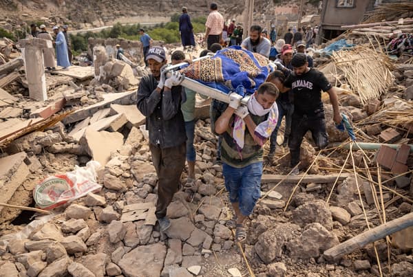 Des personnes portent les restes d'une victime du séisme meurtrier de magnitude 6,8 du 8 septembre, dans le village d'Imi N'Tala près d'Amizmiz, au centre du Maroc, le 10 septembre 2023.