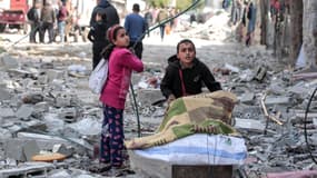 Des enfants palestiniens récupèrent certains objets trouvés au milieu des destructions causées par les bombardements israéliens à Bureij, dans le centre de la bande de Gaza, le 14 mars 2024, alors que la guerre entre Israël et le mouvement Hamas se poursuit.