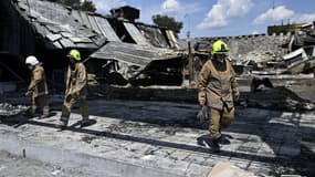 ILLUSTRATION - Des sauveteurs marchent dans le centre commercial Amstor détruit à Krementchouk, le 29 juin 2022, deux jours après qu'il a été touché par une frappe de missile russe selon les autorités ukrainiennes.