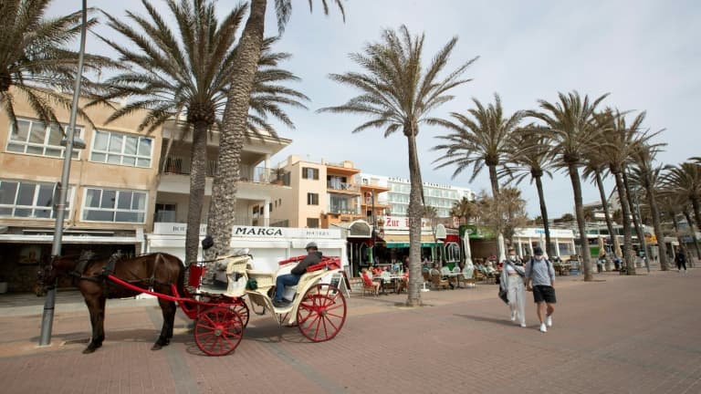 Un couple de touristes marche près de Palm Beach à Palma de Majorque le 26 mars 2021