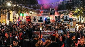 Des habitants lèvent les portraits des victimes de l'effondrement de plusieurs bâtiments dans le centre ville de Marseille.