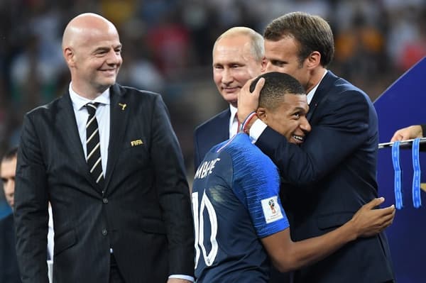 Emmanuel Macron holding Kylian Mbappé in his arms during the 2018 World Cup final ceremony
