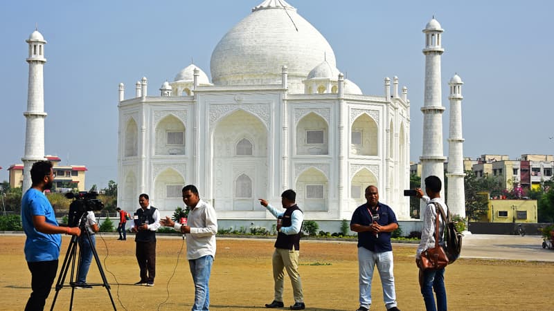 Des journalistes se tiennent devant une réplique du Taj Mahal à Burhanpur, dans l'État indien du Madhya Pradesh, le 25 novembre 2021.