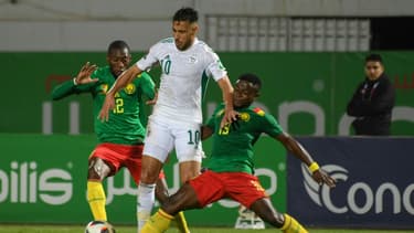Le milieu de terrain algérien Sofiane Feghouli (C) dispute le ballon à l'attaquant camerounais Karl Toko Ekambi et au défenseur camerounais Collins Fai lors du match retour des éliminatoires de la Coupe du monde de football du Qatar 2022 entre l'Algérie et le Cameroun au stade de Blida, le 29 mars 2022