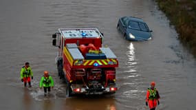 Des secouristes passent devant une voiture près de la rivière Hérault, qui a débordé à la suite de fortes pluies à Agde, dans le sud de la France, le 23 décembre 2025.