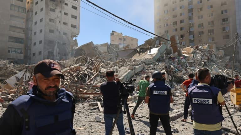 Des journalistes filment les décombres du bâtiment qui abritait les bureaux locaux de la chaîne qatarie Al-Jazeera et de l'agence internationale américaine Associated Press (AP) le 15 mai 2021 à Gaza