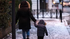 Une femme et un enfant marchent dans une rue enneigée de Mulhouse, dans l'est de la France, le 8 janvier 2024.