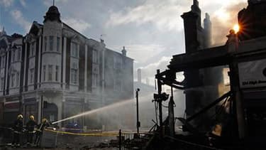 Pompiers à l'oeuvre dans une rue de Tottenham, dimanche matin. Londres se préparait dimanche à une reprise possible des violences dans ce quartier du nord de la capitale après des émeutes sans précédent depuis des années, que les milieux politiques et la