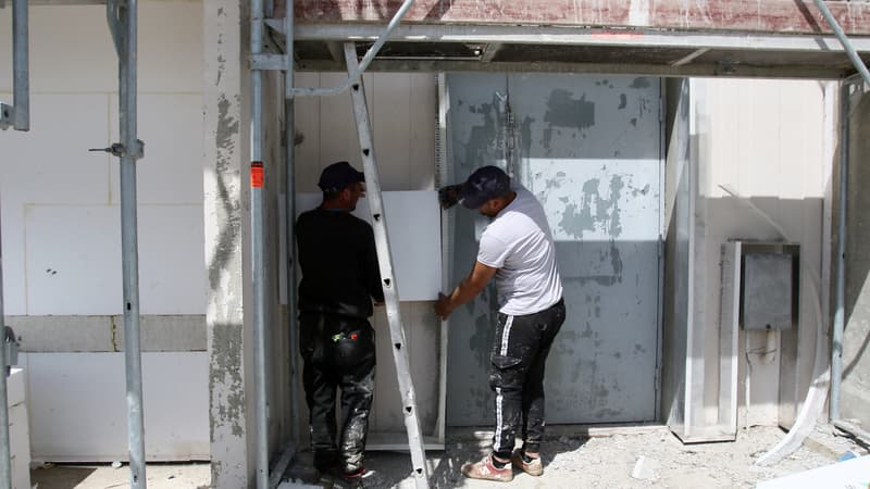 Des ouvriers du bâtiment collent un morceau de panneaux isolants en polystyrène devant un bâtiment d'HLM (Habitat à loyer modere) lors de travaux de rénovation thermique et énergétique (photo d'illustration). 