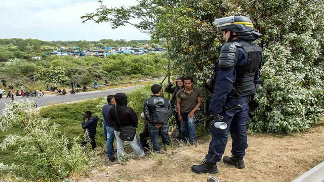 Un CRS se tenant devant un groupe de migrants (illustration)
