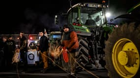 Des manifestants préparent des conteneurs d'eau lestés à suspendre lors d'une manifestation organisée par les syndicats agricoles français FNSEA et Jeunes Agriculteurs des départements de Seine-Maritime et de l'Eure pour protester contre les accords UE-Mercosur sur le pont de Tancarville, à Tancarville, le 26 novembre 2025.