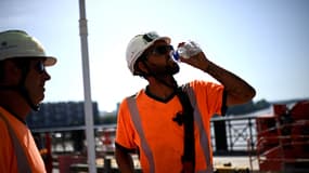 Un ouvrier boit de l'eau pour se rafraîchir pendant qu'il travaille sur le chantier de renforcement du Pont de Pierre, lors d'une vague de chaleur à Bordeaux, dans le sud-ouest de la France, le 30 juin 2025.