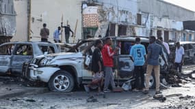 Un groupe de personnes regarde les débris et la destruction d'un café à Mogadiscio, capitale de la Somalie, le 15 juillet 2024 suite à l'explosion d'une voiture piégée où neuf personnes ont été tuées, dans la soirée du 14 juillet 2024.