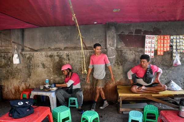 Des livreurs s'assoient et se reposent dans un restaurant de rue pendant la canicule à Yangon, le 29 avril 2024.