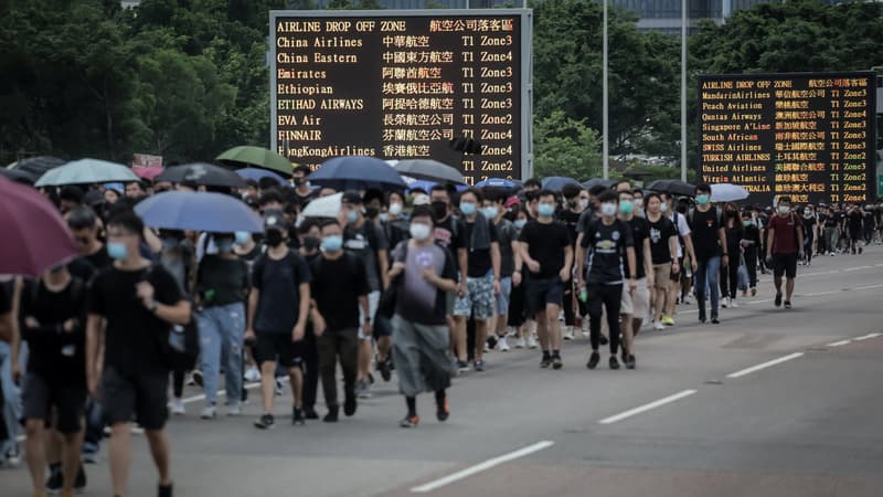 Des manifestants brandissant des parapluies près de l'aéroport.