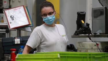 Une salariée de l'usine Valeo travaille avec un masque
