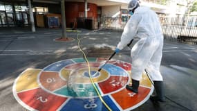 Un homme désinfecte la cour de récréation d'une école à Paris le 7 mai 2020 (photo d'illustration)