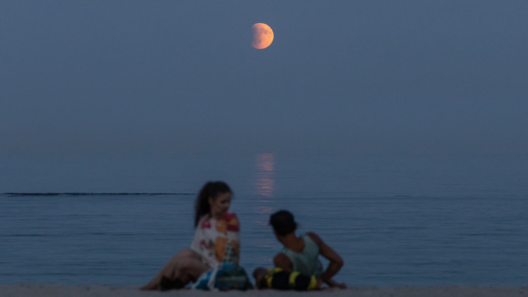 Des baigneurs se reposent sur une plage de la mer Noire sous une pleine lune pendant une éclipse totale en arrière-plan à Odessa, le 7 septembre 2025. Des baigneurs se reposent sur une plage de la mer Noire sous une pleine lune pendant une éclipse totale en arrière-plan à Odessa, le 7 septembre 2025.