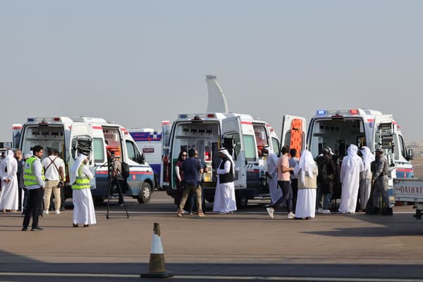Wolontariusze i karetki czekają na płycie lotniska w Abu Zabi 18 listopada 2023 r. na przylot samolotu przewożącego Palestyńczyków ewakuowanych z Gazy w ramach misji humanitarnej zorganizowanej przez Zjednoczone Emiraty Arabskie.