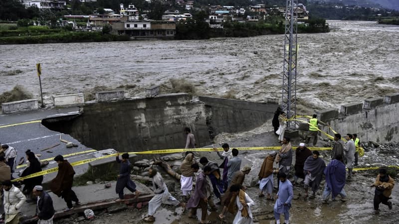 Des personnes près d'une route détruite par les pluies dans la vallée du Swat, le 27 août 2022.