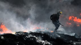 Un manifestant escalade un amont d'ordures brûlées, jeudi 23 janvier, à Kiev.