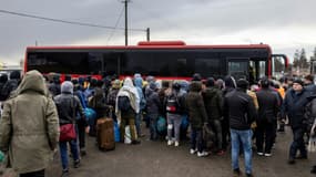 Des réfugiés de différents pays arrivés à pied en Pologne après avoir fui les combats en Ukraine, attendent de monter à bord d'un bus, le 27 février 2022 à Medyka