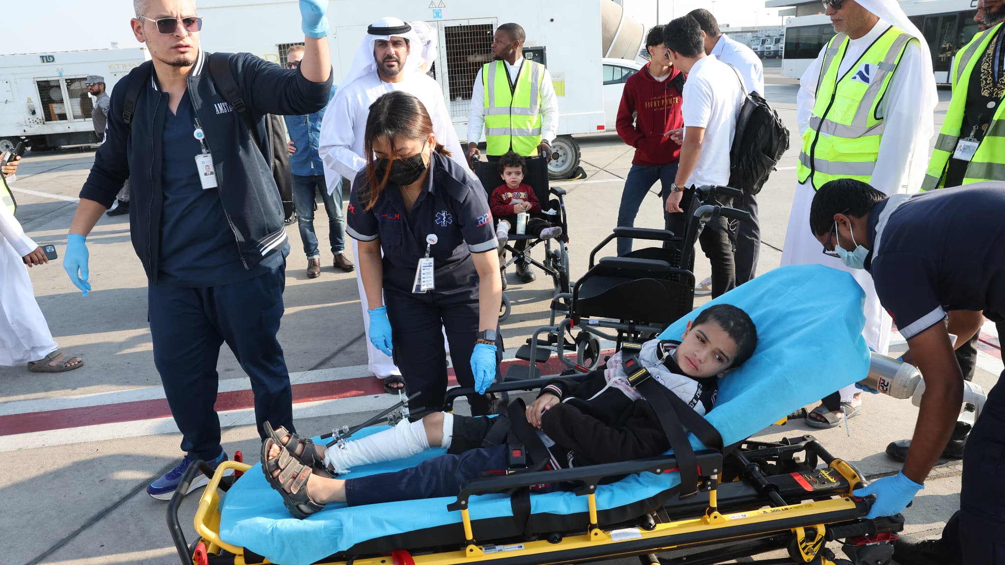 Des volontaires transportent un enfant palestinien blessé hors de l'avion à leur arrivée à Abu Dhabi le 18 novembre 2023, après avoir été évacués de Gaza dans le cadre d'une mission humanitaire organisée par les Émirats arabes unis.