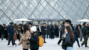 Des visiteurs devant la pyramide conçue par l'architecte sino-américain Ieoh Ming Pei et le musée du Louvre fermé lors d'une assemblée générale de ses personnels, appelés à la grève, le 15 décembre 2025 à Paris