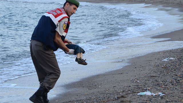 Un officier de police turc devant le corps d'un enfant migrant retrouvé mort sur une plage de Bodrum, au sud de la Turquie, le 2 septembre 2015.