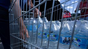 Un homme met des bouteilles d'eau dans sa voiture sur le parking d'un supermarché à Gérardmer dans l'est de la France, le 3 août 2022