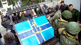 Derrière des militaires russes en faction, des militants pro-russes démontent et emportent la grille du siège de la marine ukrainienne à Sébastopol. Le bâtiment est contrôlé depuis quelques heures par l’armée russe.