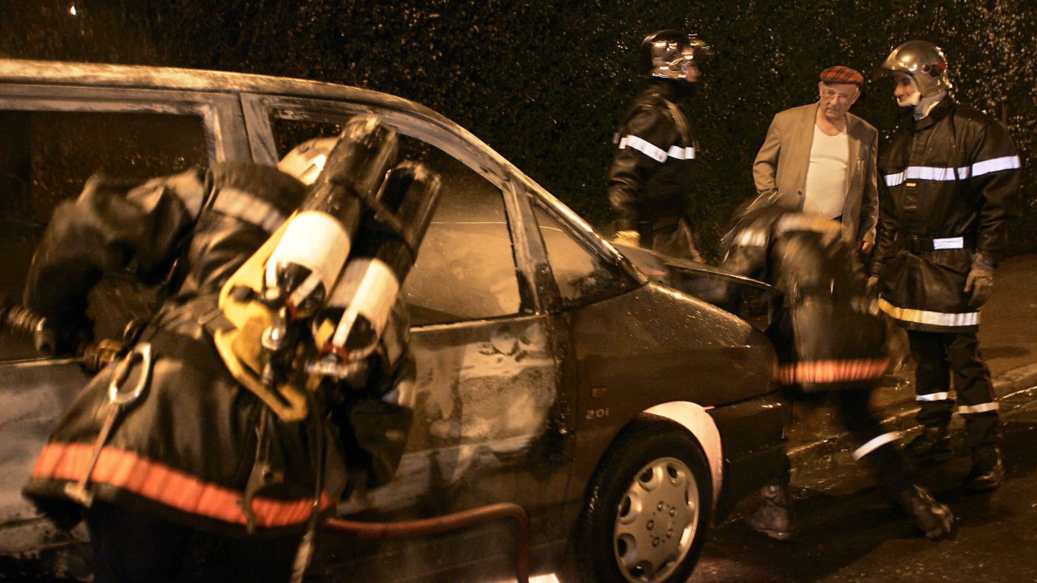 Le propriétaire d'une voiture incendiée lors d'émeutes s'entretient avec les pompiers le 8 novembre 2005 dans le quartier de Lomme, à Lille.