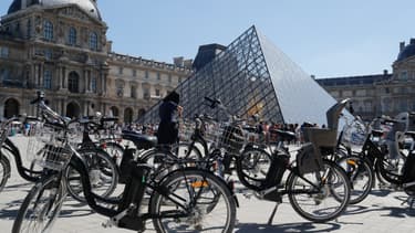 Des vélos électriques devant la pyramide du Louvre.