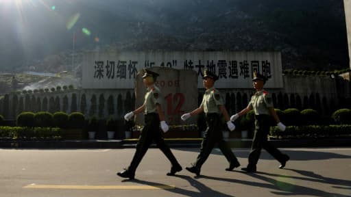 Des policiers passent, le 12 mai 2013, devant le monument dédié aux victimes du tremblement de terre de 2008, qui avait fait 87.000 morts et disparus dans la province du Sichuan, en Chine