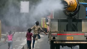 Des enfants courent derrière un camion pulvérisant de l'eau le long d'une rue par une chaude journée d'été à New Delhi, le 28 mai 2024.