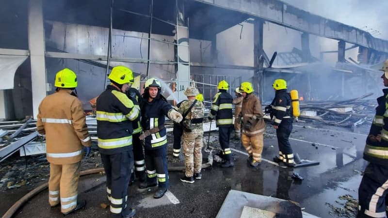 Des pompiers ukrainiens tentent d'éteindre le feu déclenché suite à une frappe sur le centre commercial de Krementchouk dans le centre de l'Ukraine, le 27 juin 2022