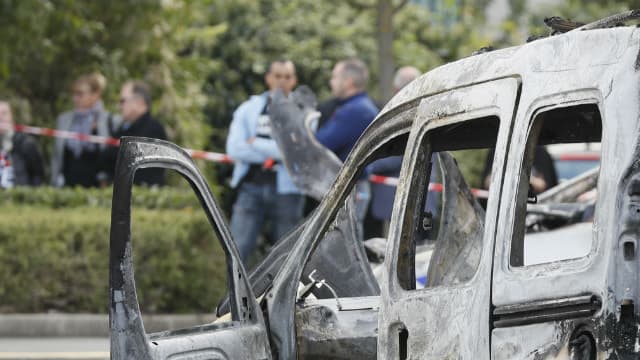 Un officier de police monte la garde près d'un véhicule de police incendié et d'une camionnette à Viry-Châtillon, le 8 octobre 2016.