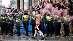 Un supporter anglais passe devant la police à Trafalgar Square, avant le début de la finale de l'Euro 2020, entre l'Angleterre et l'Italie, le 11 juillet 2021 au stade de Wembley à Londres