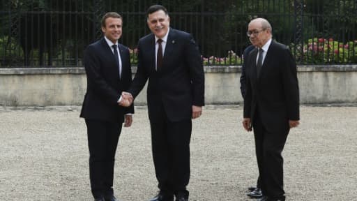 Le président Emmanuel Macron et le chef du gouvernement de Tripoli Fayyez al-Sarraj se serrent la main, accompagnés du ministre français des Affaires étrangères Jean-Yves Le Drian, à La Celle-Saint-Cloud, près de Paris, le 25 juillet 2017