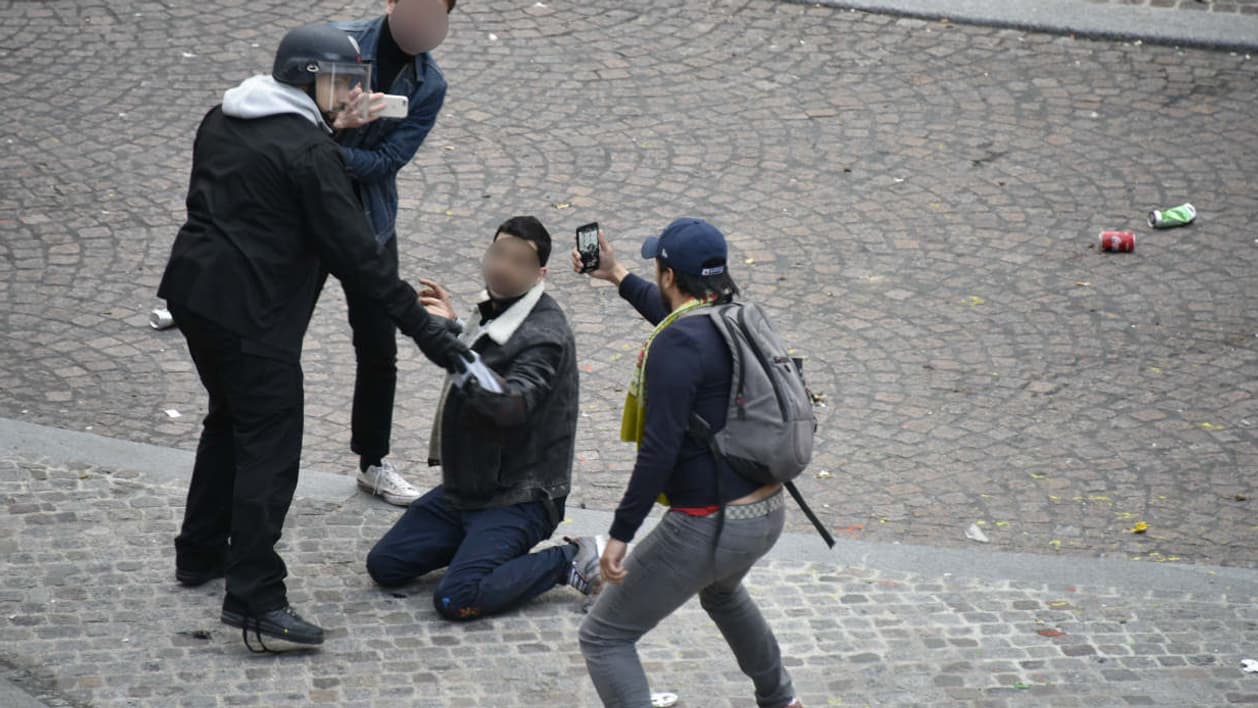 Alexandre Benalla maintient à terre le jeune manifestant place de la Contrescarpe à Paris, tandis qu'un homme filme la scène le 1er mai dernier.